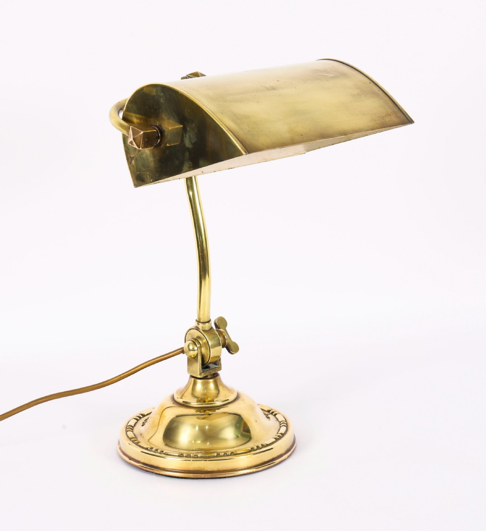 An Art Deco articulated brass desk lamp featuring a curved adjustable arm, a rectangular brass shade, and a moulded circular base. View V