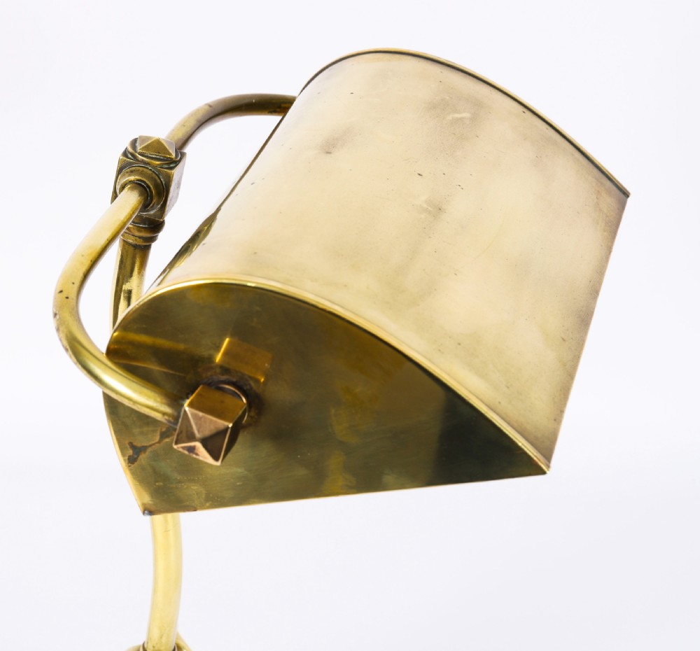 An Art Deco articulated brass desk lamp featuring a curved adjustable arm, a rectangular brass shade, and a moulded circular base. View VI