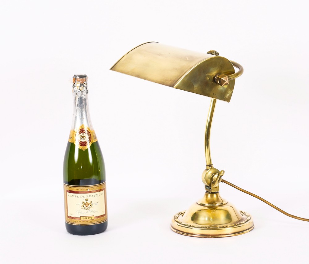 An Art Deco articulated brass desk lamp featuring a curved adjustable arm, a rectangular brass shade, and a moulded circular base. View XI