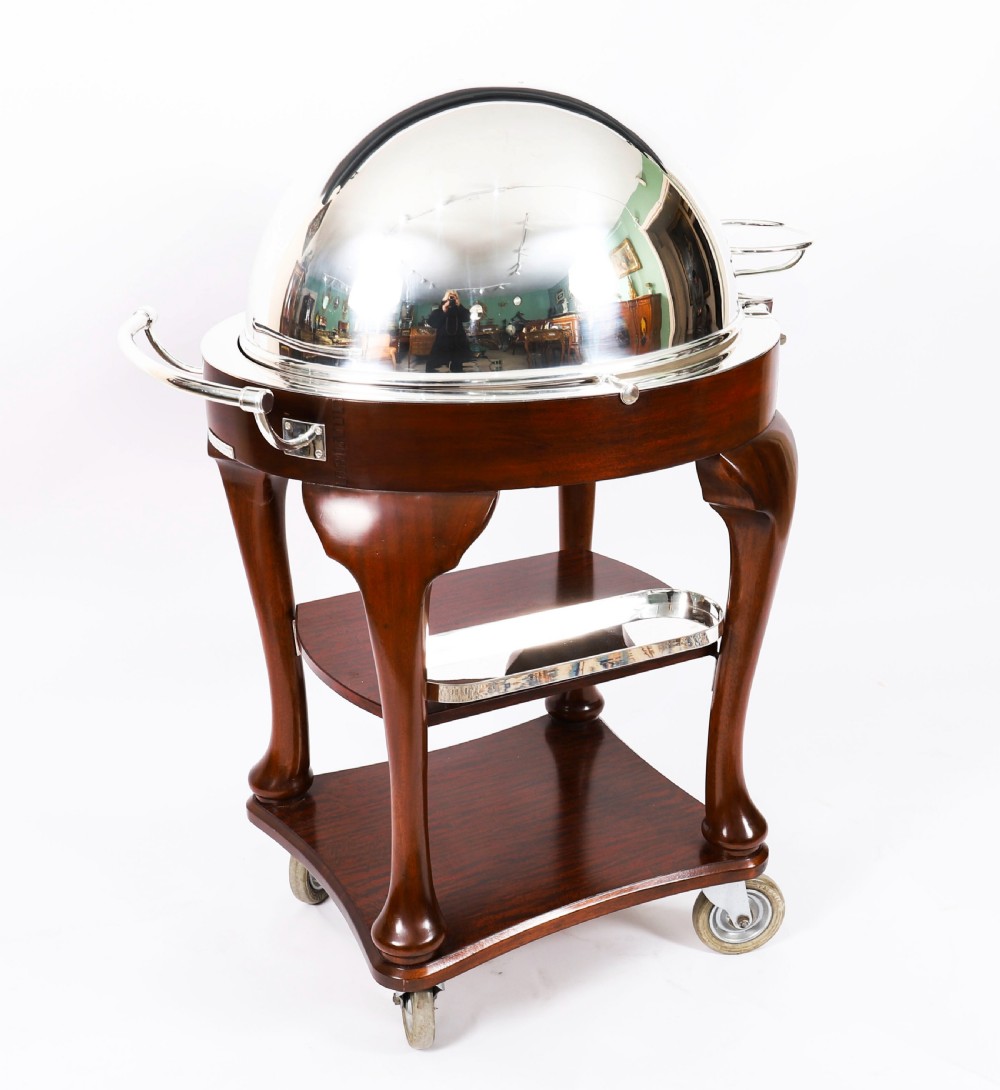 An Art Deco silver-plated beef carving trolley with a hemispherical revolving dome cover mounted on a dark mahogany frame with cabriole legs.