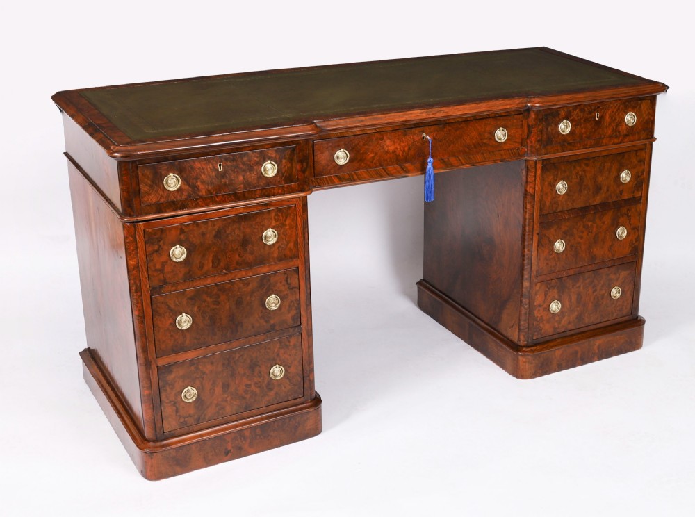 A nineteenth-century Victorian burr walnut twin pedestal desk featuring a green leather writing insert, brass ring handles, and multiple drawers.
