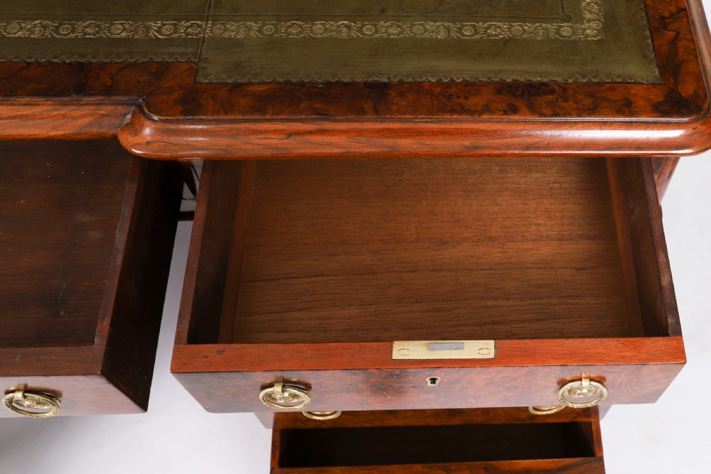 A nineteenth-century Victorian burr walnut twin pedestal desk featuring a green leather writing insert, brass ring handles, and multiple drawers. View IX