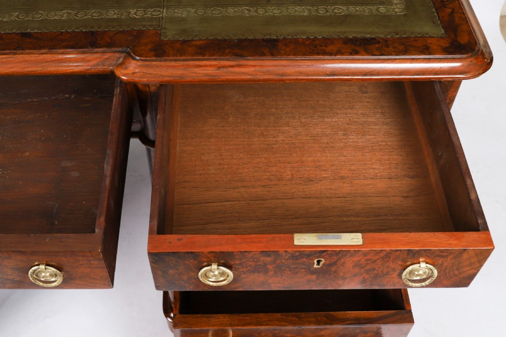 A nineteenth-century Victorian burr walnut twin pedestal desk featuring a green leather writing insert, brass ring handles, and multiple drawers. View X