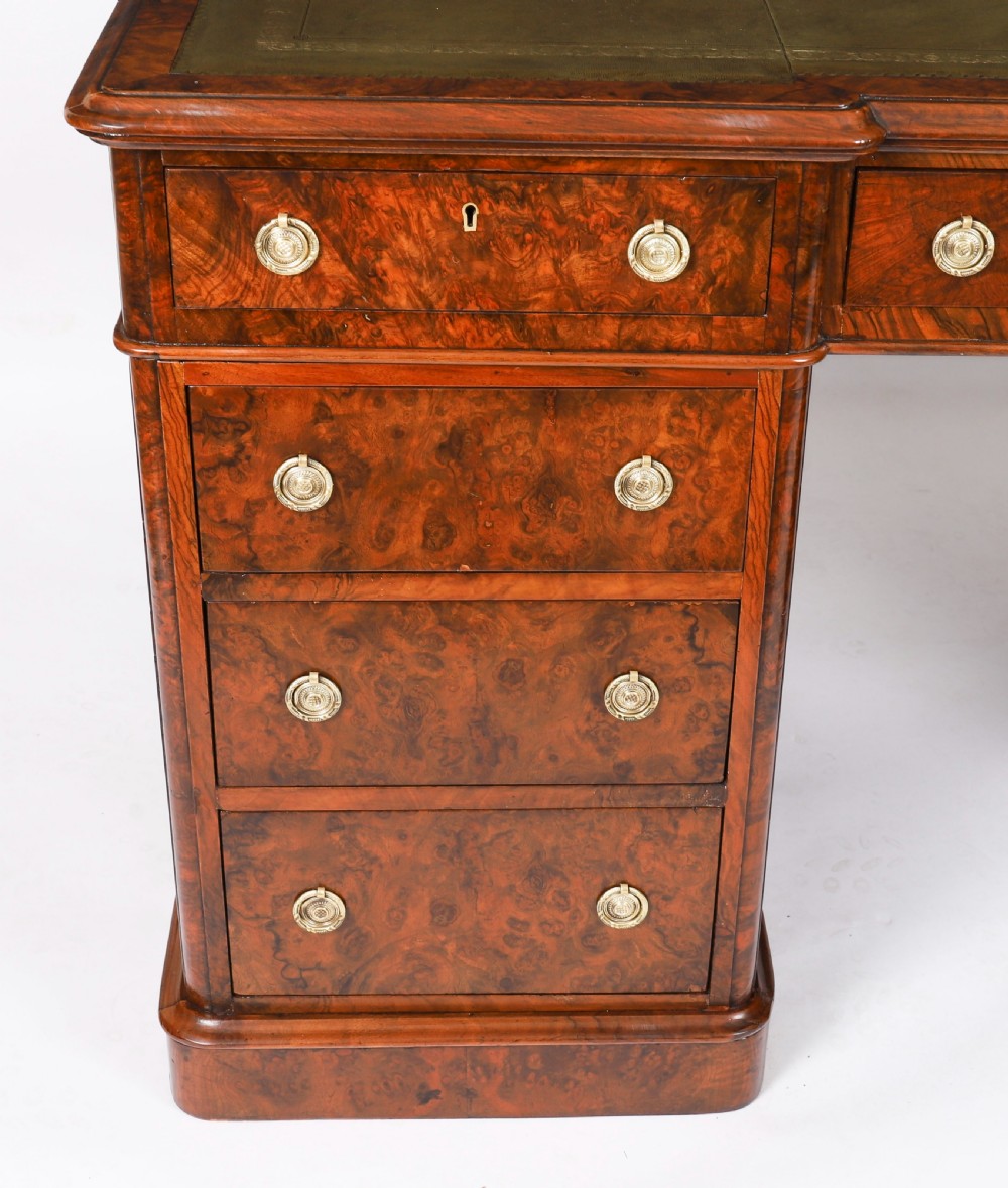 A nineteenth-century Victorian burr walnut twin pedestal desk featuring a green leather writing insert, brass ring handles, and multiple drawers. View XV