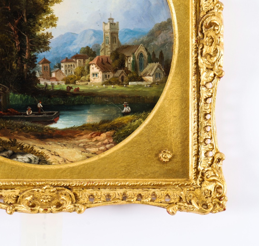 A pair of nineteenth-century oil paintings on board depicting river scenes with figures and ruins, housed in square gilded frames with circular tondo apertures. View XIV