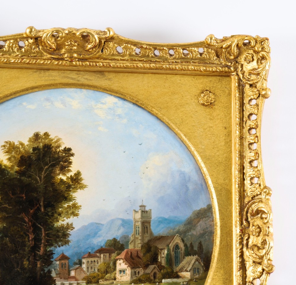 A pair of nineteenth-century oil paintings on board depicting river scenes with figures and ruins, housed in square gilded frames with circular tondo apertures. View XIX