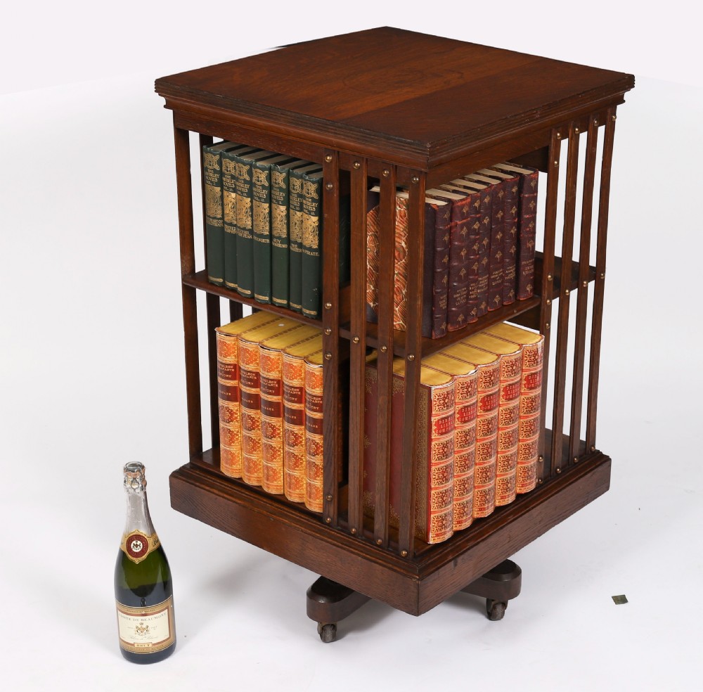 A two-tier Victorian dark oak revolving bookcase with vertical side slats and brass studs, raised on a quadruped base with metal castors. View VIII
