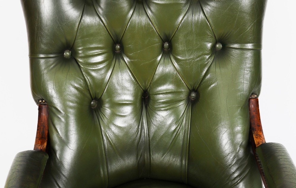 A pair of Victorian 19th-century armchairs upholstered in deep-buttoned green leather with dark mahogany frames and turned front legs on castors. View VI