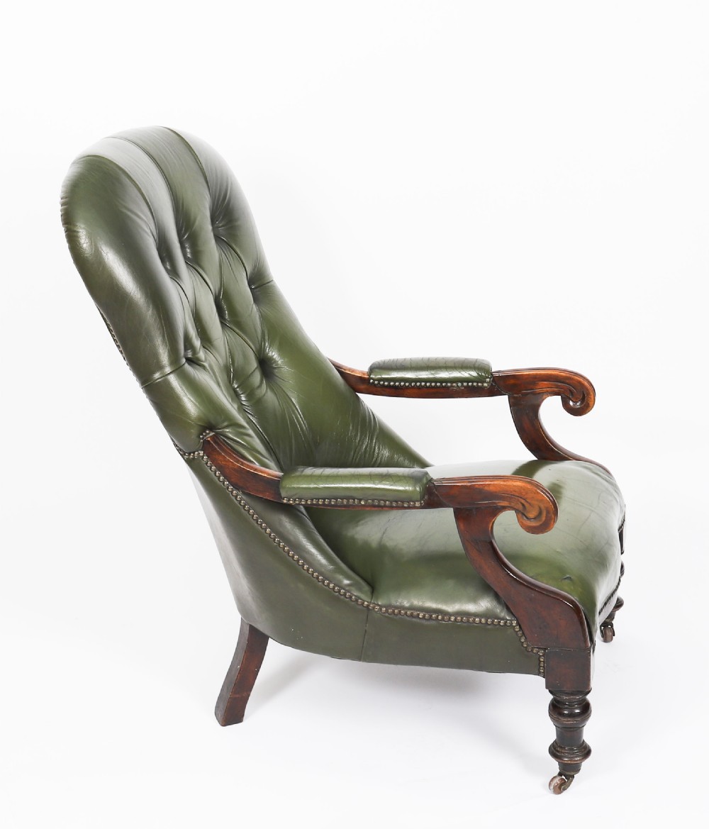 A pair of Victorian 19th-century armchairs upholstered in deep-buttoned green leather with dark mahogany frames and turned front legs on castors. View IX