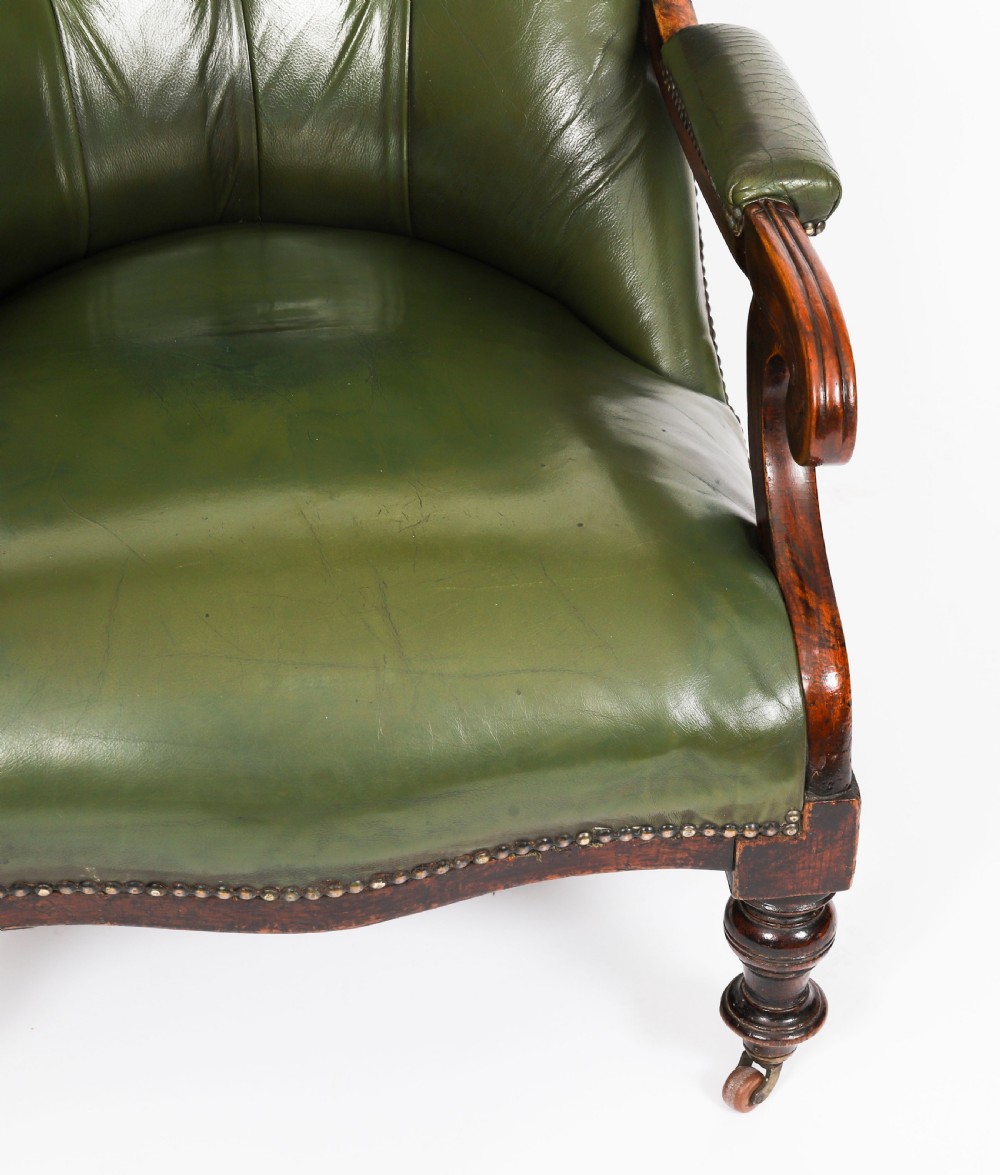 A pair of Victorian 19th-century armchairs upholstered in deep-buttoned green leather with dark mahogany frames and turned front legs on castors. View X