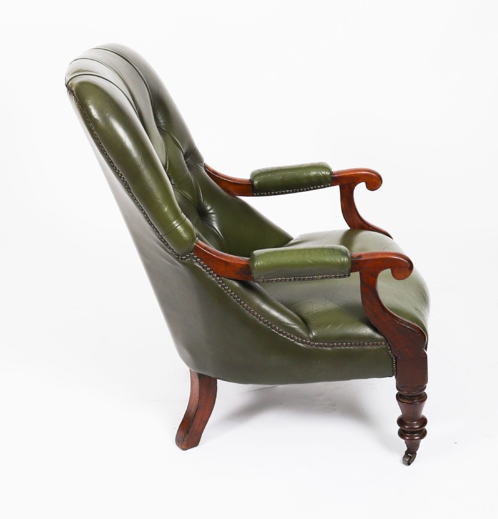 A pair of Victorian 19th-century armchairs upholstered in deep-buttoned green leather with dark mahogany frames and turned front legs on castors. View XII