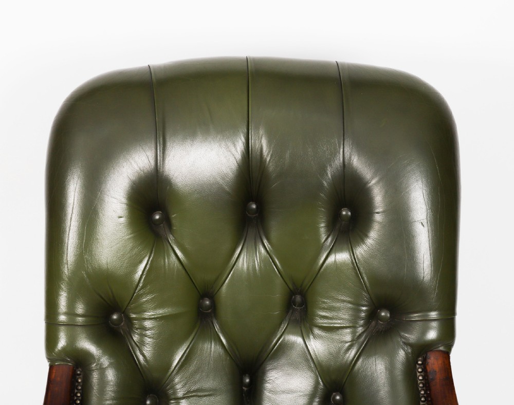 A pair of Victorian 19th-century armchairs upholstered in deep-buttoned green leather with dark mahogany frames and turned front legs on castors. View XIV