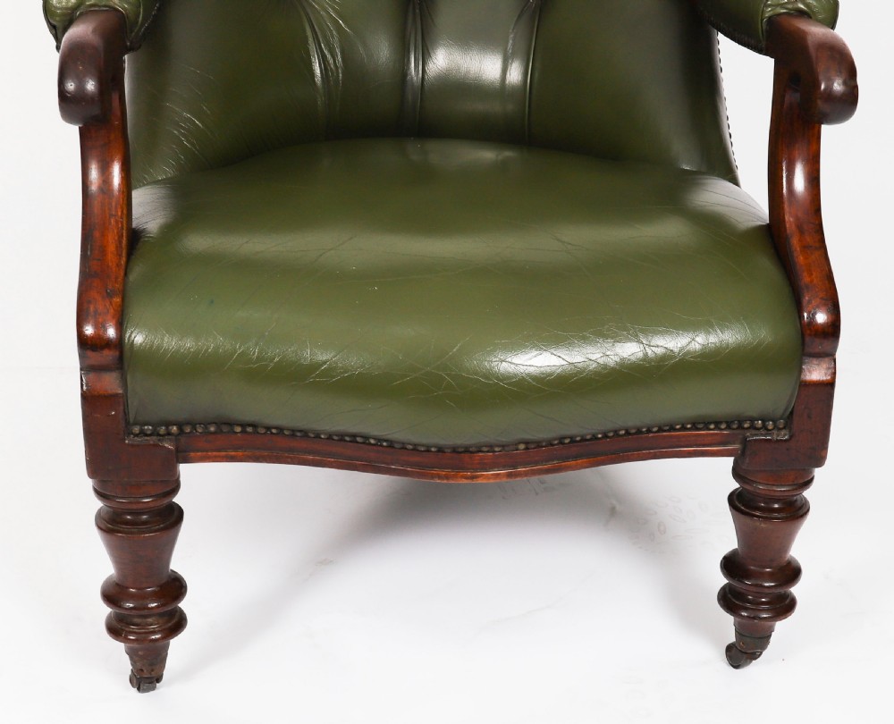 A pair of Victorian 19th-century armchairs upholstered in deep-buttoned green leather with dark mahogany frames and turned front legs on castors. View XV