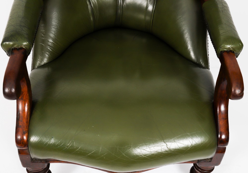 A pair of Victorian 19th-century armchairs upholstered in deep-buttoned green leather with dark mahogany frames and turned front legs on castors. View XVI