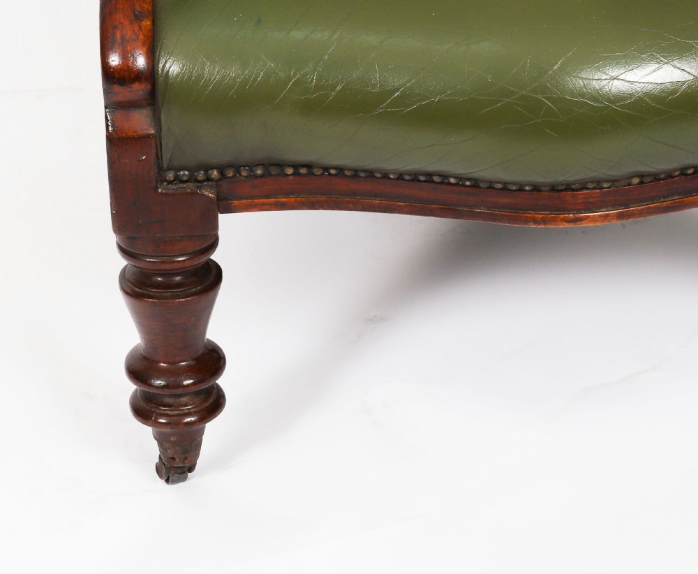 A pair of Victorian 19th-century armchairs upholstered in deep-buttoned green leather with dark mahogany frames and turned front legs on castors. View XVII