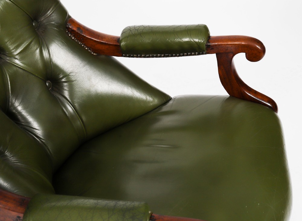 A pair of Victorian 19th-century armchairs upholstered in deep-buttoned green leather with dark mahogany frames and turned front legs on castors. View XVIII