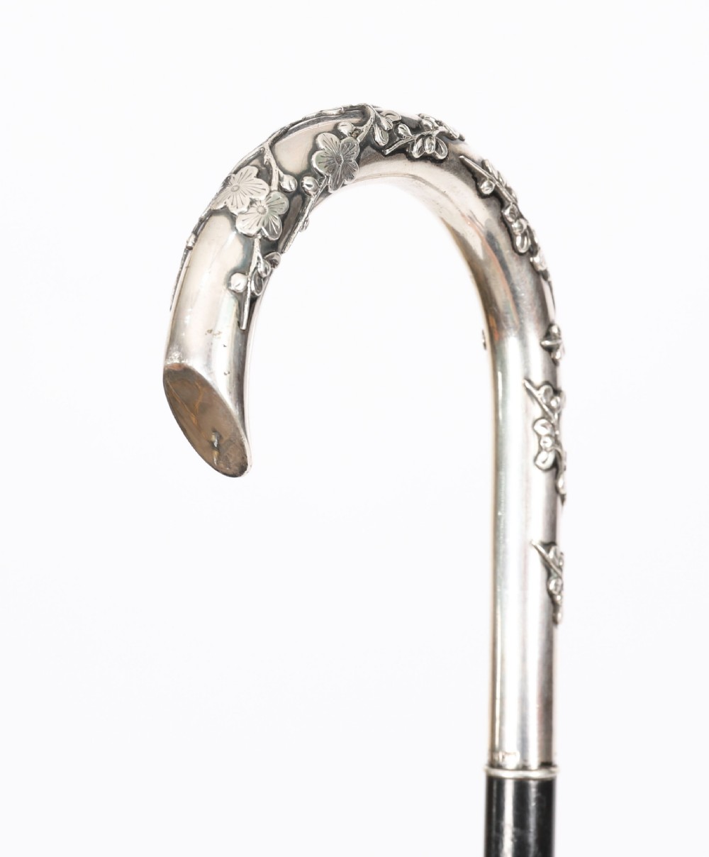 A 19th-century walking cane featuring a curved silver crook handle embossed with cherry blossom motifs attached to a dark wood shaft. View III