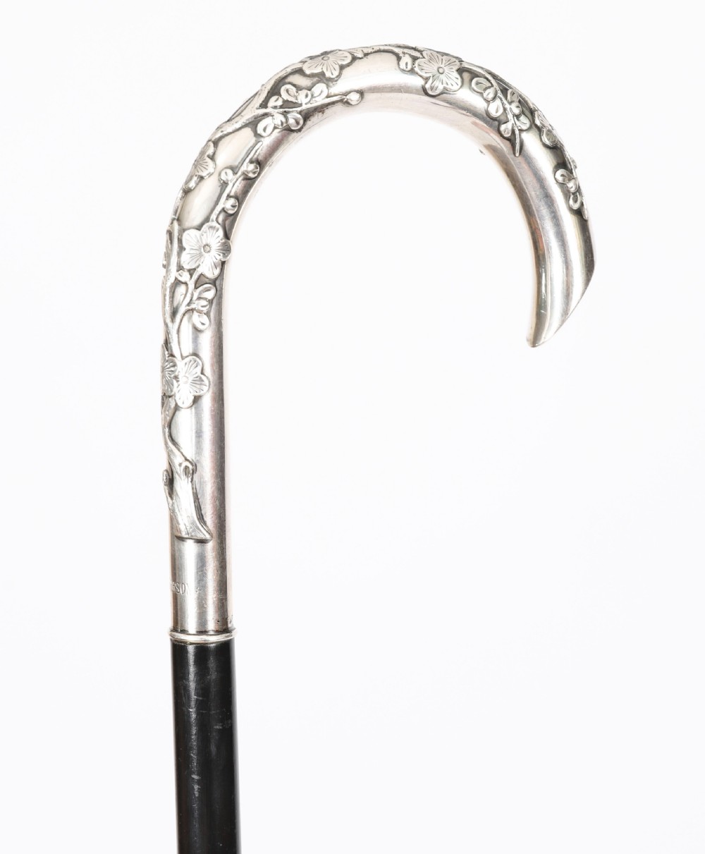 A 19th-century walking cane featuring a curved silver crook handle embossed with cherry blossom motifs attached to a dark wood shaft. View IV