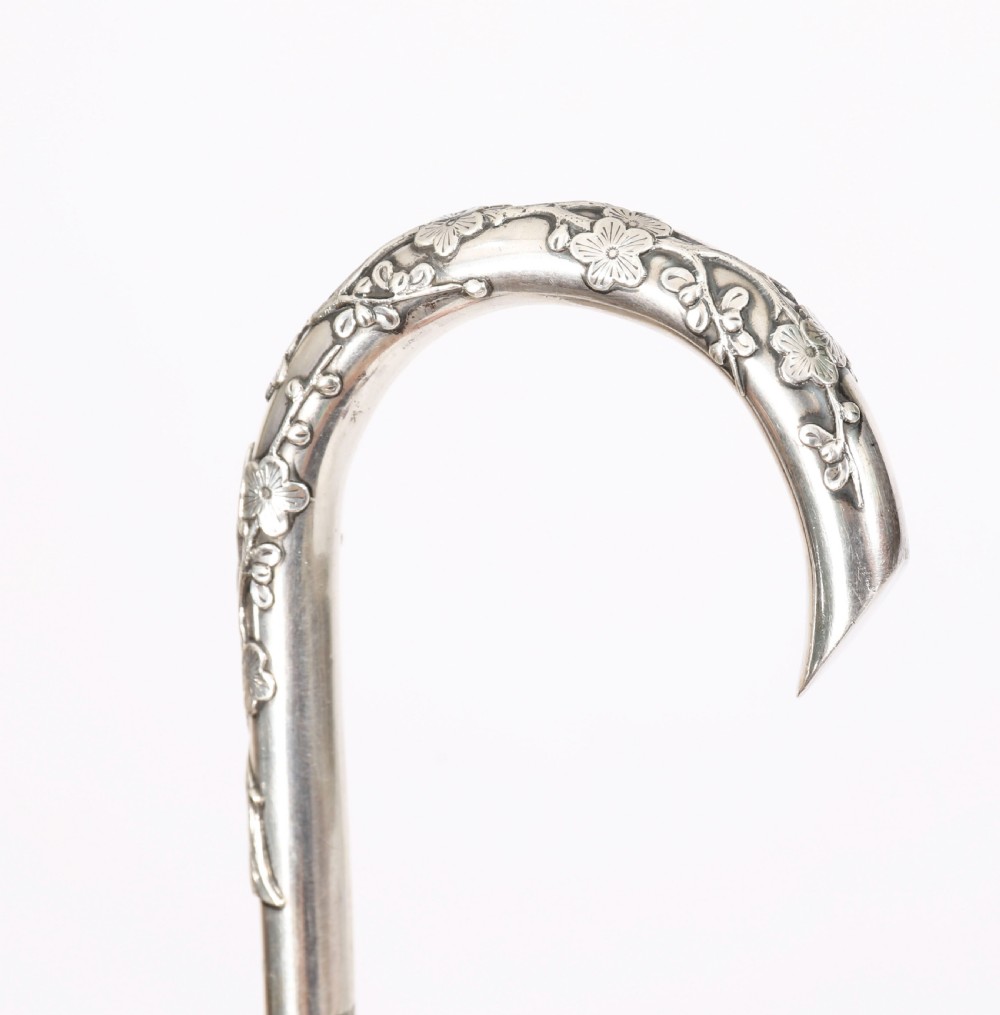 A 19th-century walking cane featuring a curved silver crook handle embossed with cherry blossom motifs attached to a dark wood shaft. View V