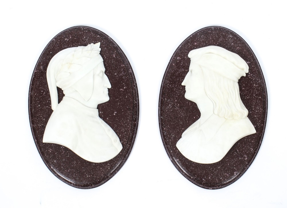 A pair of 19th-century oval plaques featuring white carved marble profile busts of Dante and Virgil set against dark mottled stone backgrounds.