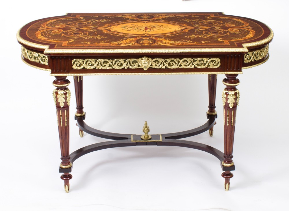 An antique French bureau plat writing table featuring detailed floral marquetry inlays, decorative gilt-bronze ormolu mounts, turned legs, and an X-frame stretcher. View II
