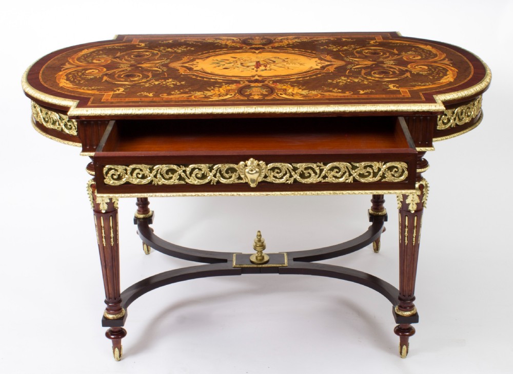 An antique French bureau plat writing table featuring detailed floral marquetry inlays, decorative gilt-bronze ormolu mounts, turned legs, and an X-frame stretcher. View III
