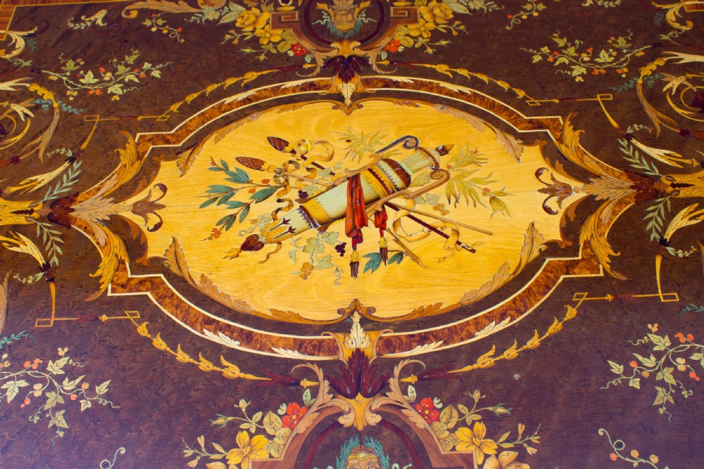 An antique French bureau plat writing table featuring detailed floral marquetry inlays, decorative gilt-bronze ormolu mounts, turned legs, and an X-frame stretcher. View VI