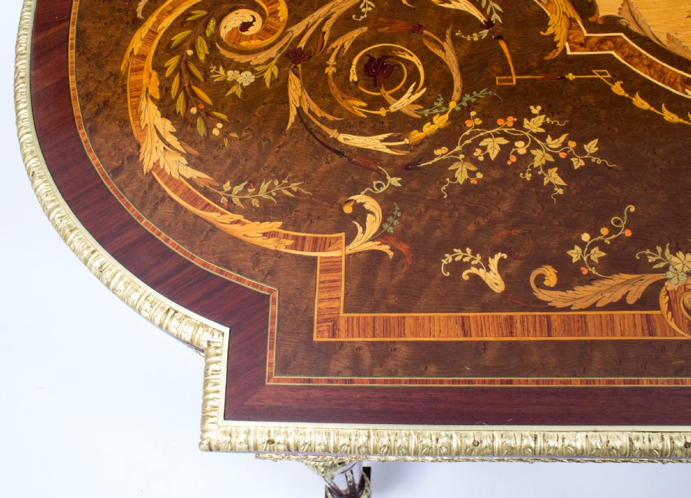 An antique French bureau plat writing table featuring detailed floral marquetry inlays, decorative gilt-bronze ormolu mounts, turned legs, and an X-frame stretcher. View VII