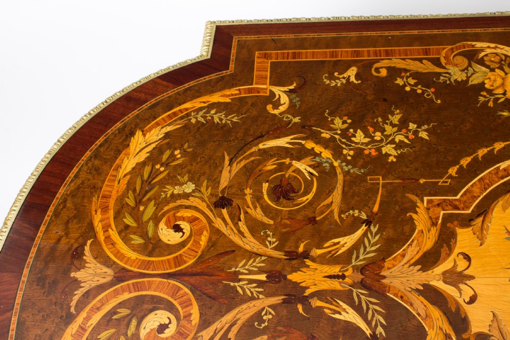 An antique French bureau plat writing table featuring detailed floral marquetry inlays, decorative gilt-bronze ormolu mounts, turned legs, and an X-frame stretcher. View VIII