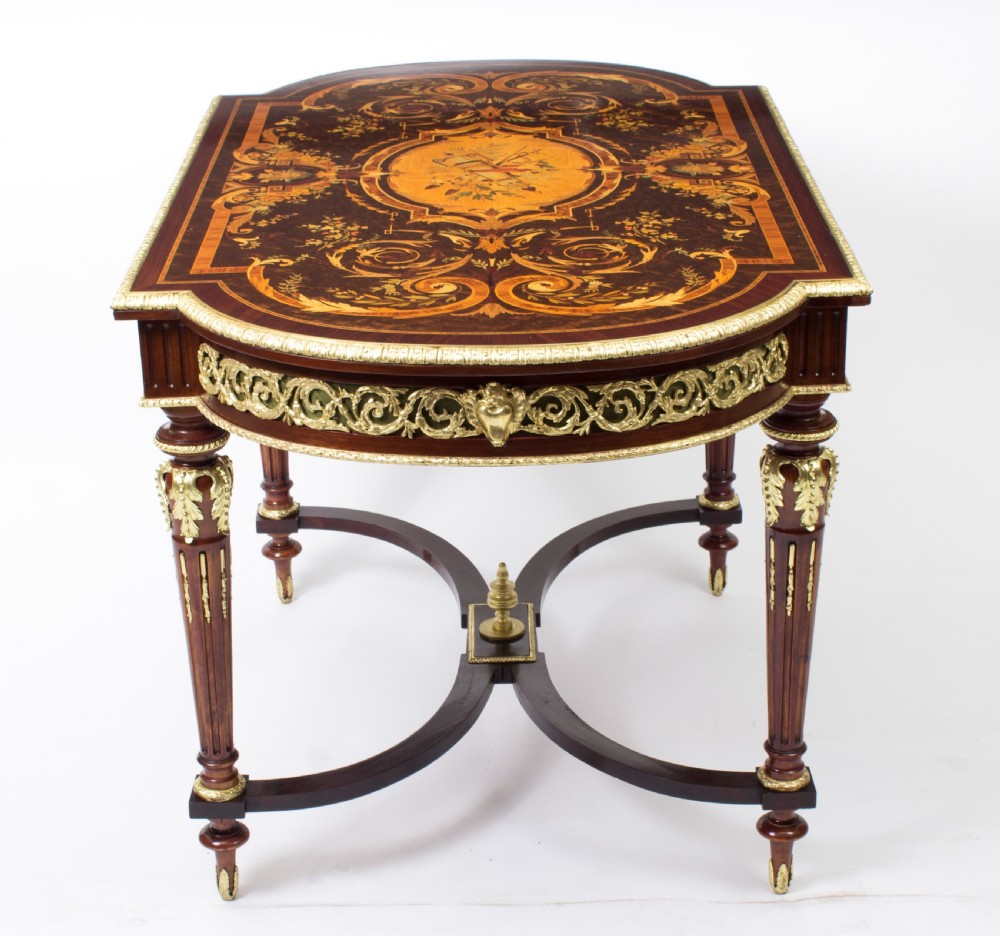 An antique French bureau plat writing table featuring detailed floral marquetry inlays, decorative gilt-bronze ormolu mounts, turned legs, and an X-frame stretcher. View XIV