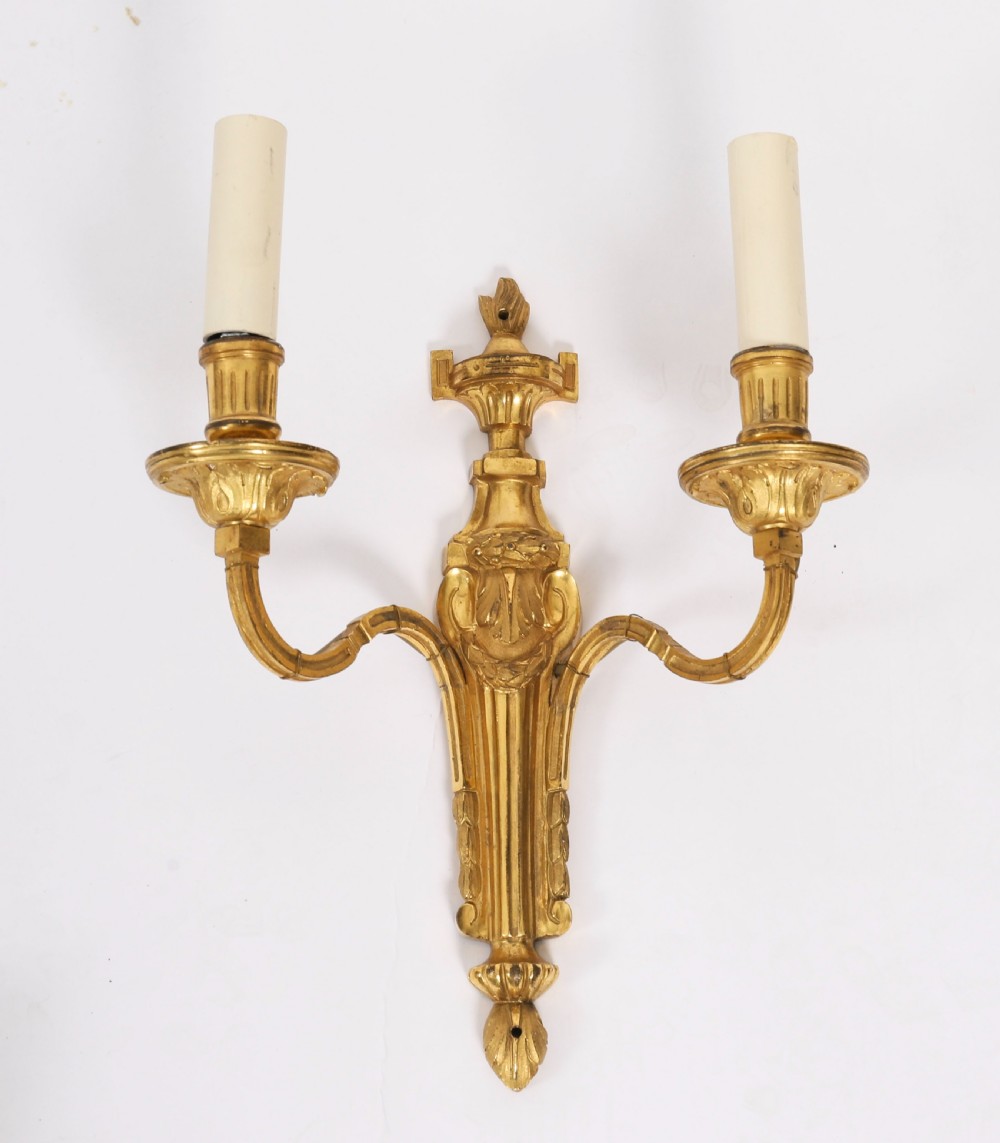 A pair of antique French Louis XVI style two-branch ormolu wall lights with fluted backplates and cream candle sleeves. View II