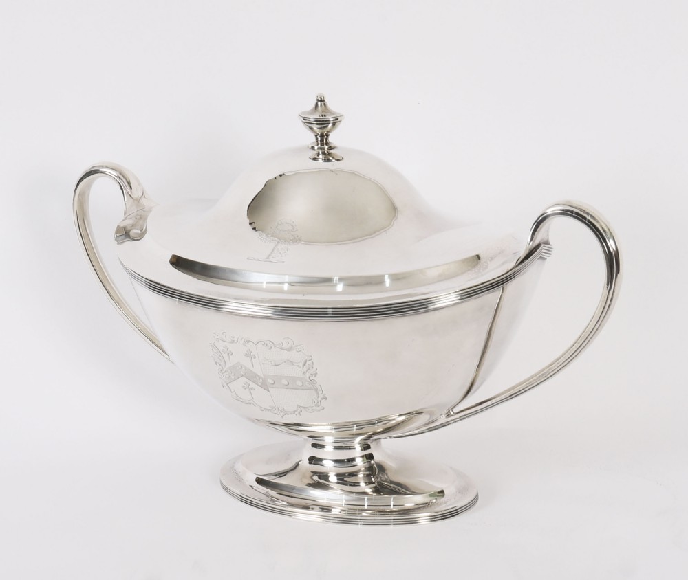 A George III sterling silver tureen with two looped handles, a domed lid, a pedestal base, and an engraved heraldic crest. View VIII