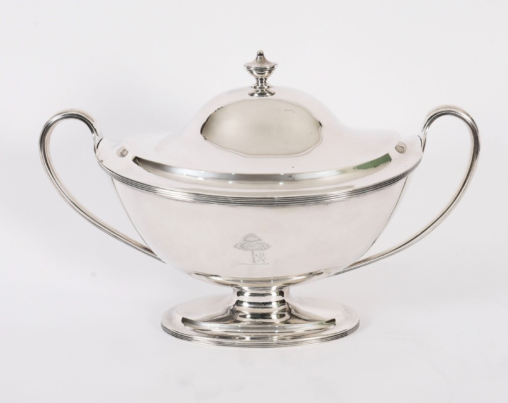 A George III sterling silver tureen with two looped handles, a domed lid, a pedestal base, and an engraved heraldic crest. View XI