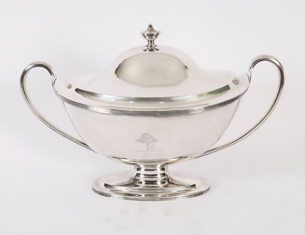 A George III sterling silver tureen with two looped handles, a domed lid, a pedestal base, and an engraved heraldic crest. View XIV
