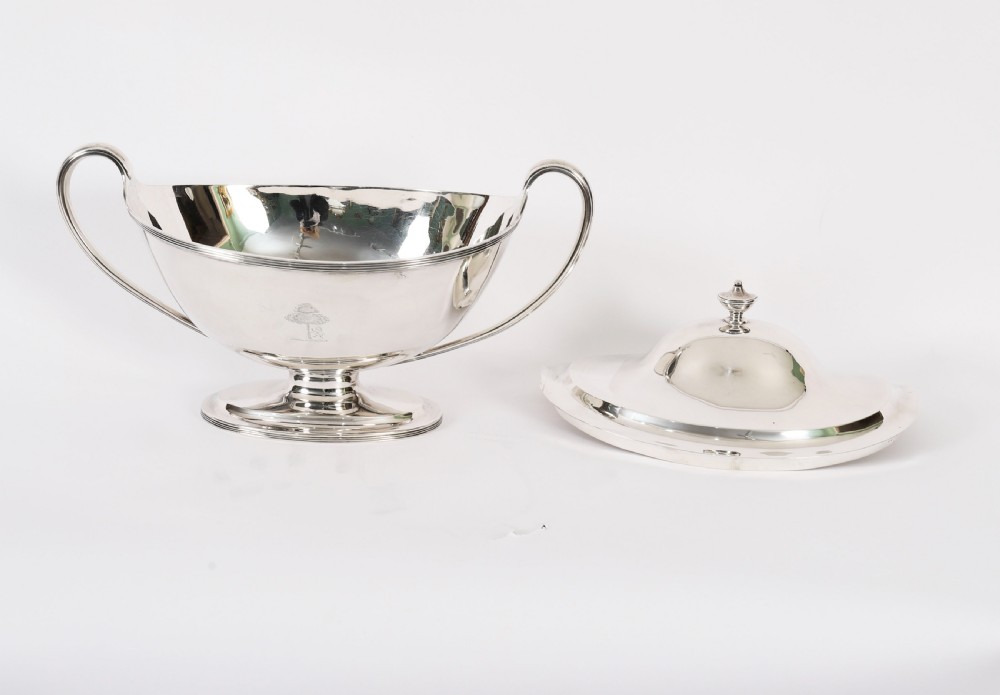 A George III sterling silver tureen with two looped handles, a domed lid, a pedestal base, and an engraved heraldic crest. View XVI