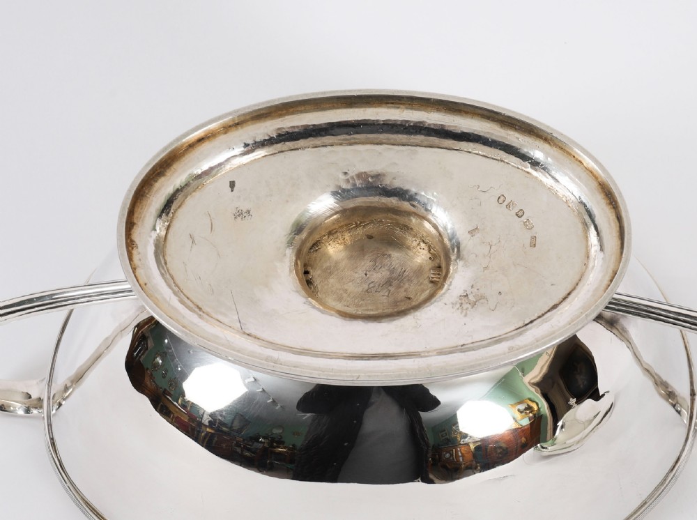 A George III sterling silver tureen with two looped handles, a domed lid, a pedestal base, and an engraved heraldic crest. View XVIII