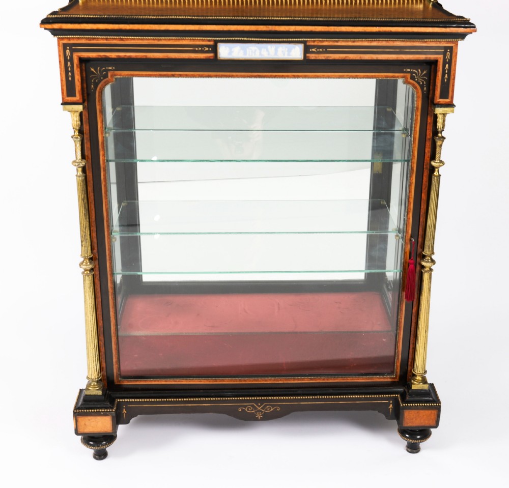 A Victorian ebonised and amboyna wood pier display cabinet featuring glass doors, interior glass shelves, and gilded brass mounts. View III