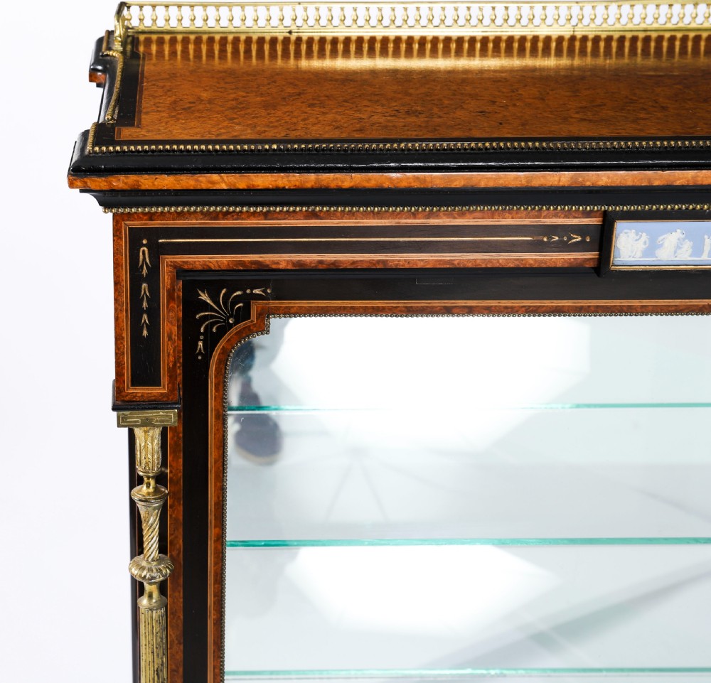 A Victorian ebonised and amboyna wood pier display cabinet featuring glass doors, interior glass shelves, and gilded brass mounts. View V