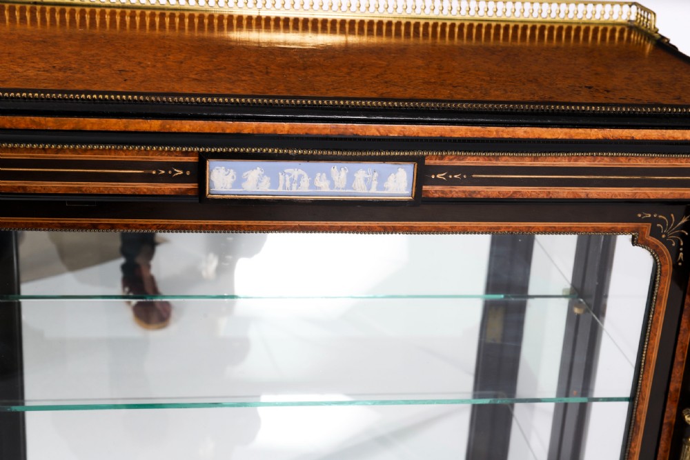 A Victorian ebonised and amboyna wood pier display cabinet featuring glass doors, interior glass shelves, and gilded brass mounts. View VI