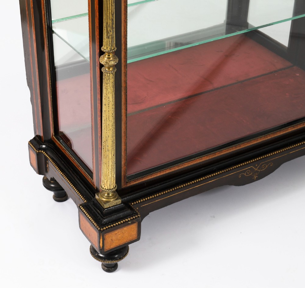 A Victorian ebonised and amboyna wood pier display cabinet featuring glass doors, interior glass shelves, and gilded brass mounts. View IX