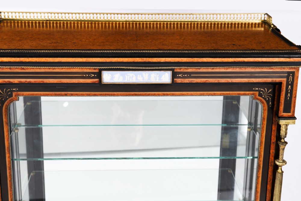 A Victorian ebonised and amboyna wood pier display cabinet featuring glass doors, interior glass shelves, and gilded brass mounts. View XV