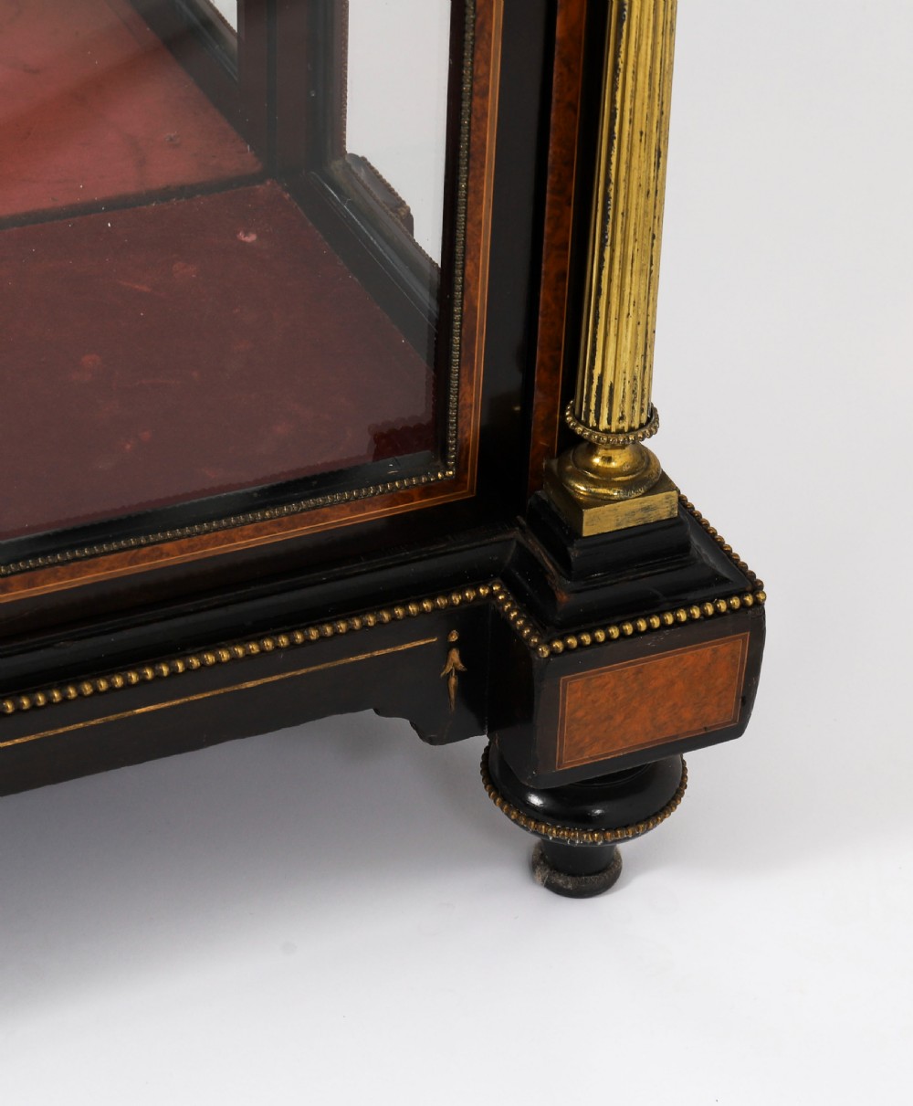 A Victorian ebonised and amboyna wood pier display cabinet featuring glass doors, interior glass shelves, and gilded brass mounts. View XVI