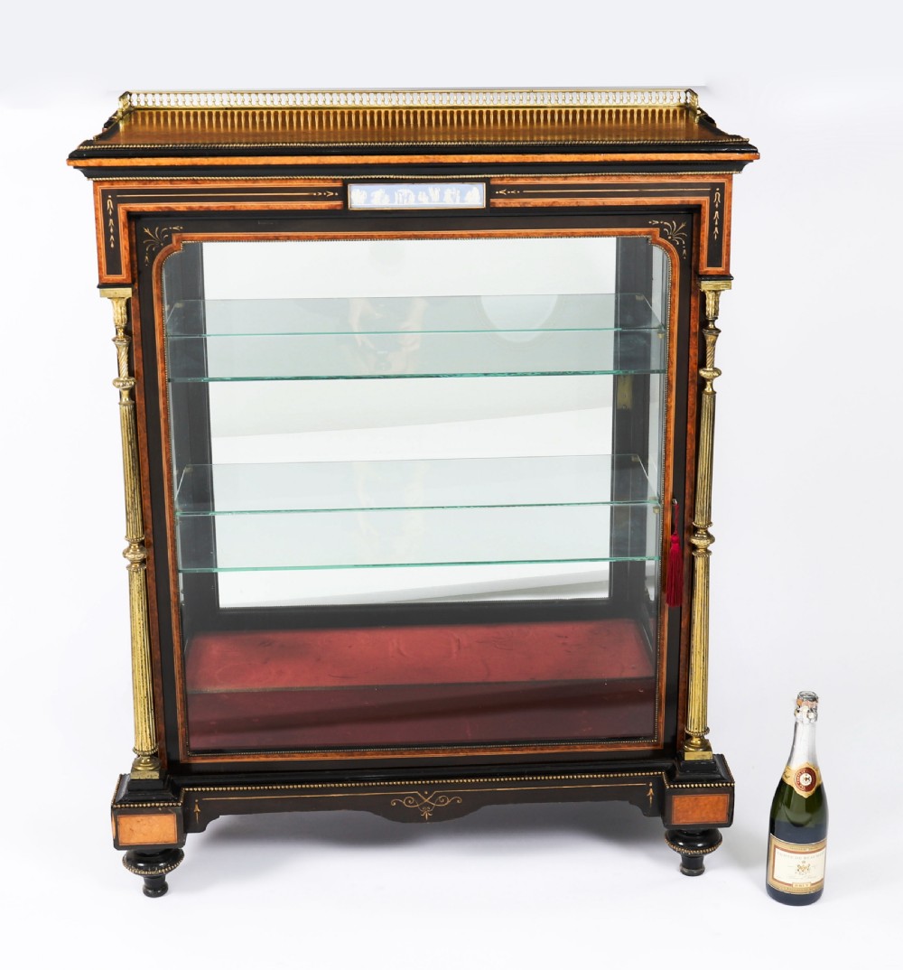 A Victorian ebonised and amboyna wood pier display cabinet featuring glass doors, interior glass shelves, and gilded brass mounts. View XVII