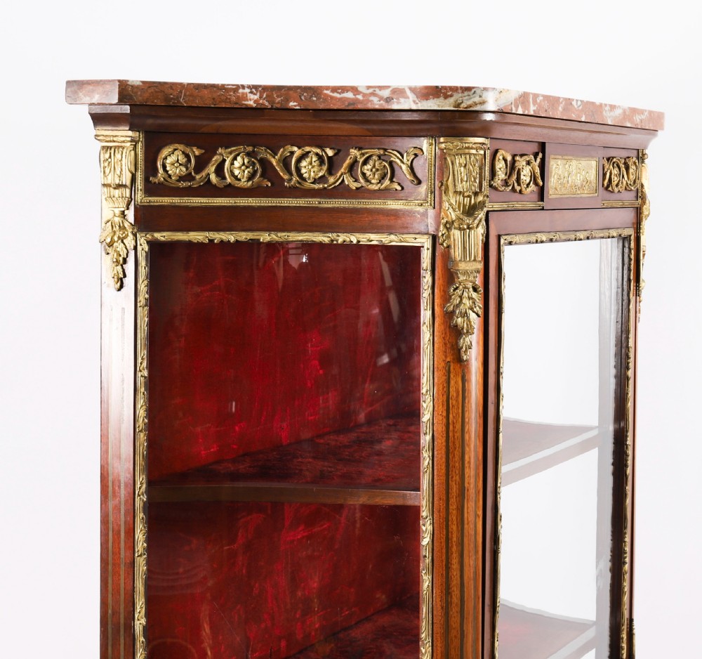 A 19th-century French Louis Revival vitrine cabinet featuring a marble top, glazed glass sides and door, floral marquetry panels, and ornate gilt bronze mounts. View IX