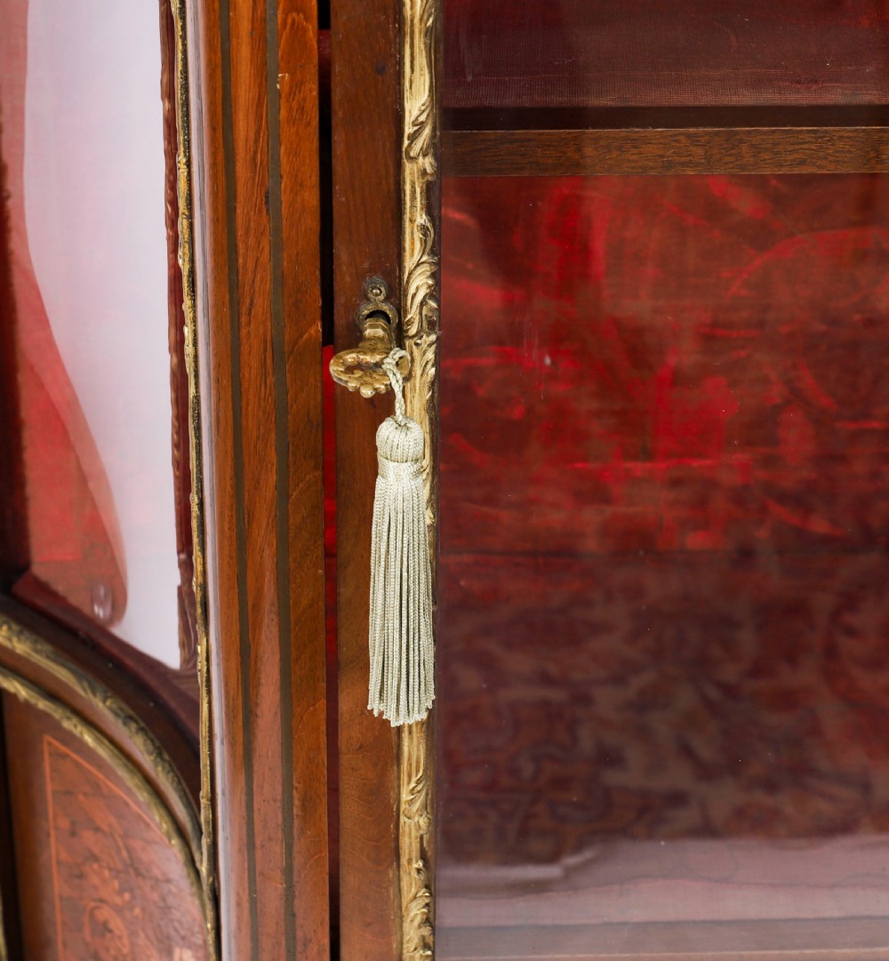 A 19th-century French Louis Revival vitrine cabinet featuring a marble top, glazed glass sides and door, floral marquetry panels, and ornate gilt bronze mounts. View XII