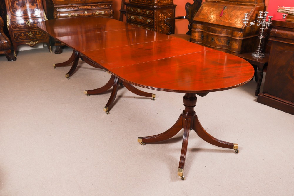 A large George IV Regency mahogany extended dining table featuring three pedestal supports with reeded legs and brass castors.