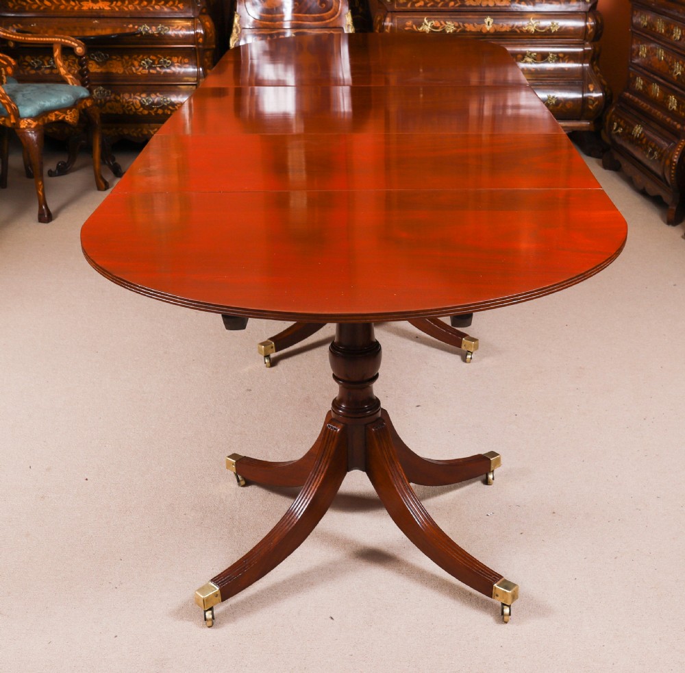 A large George IV Regency mahogany extended dining table featuring three pedestal supports with reeded legs and brass castors. View IV