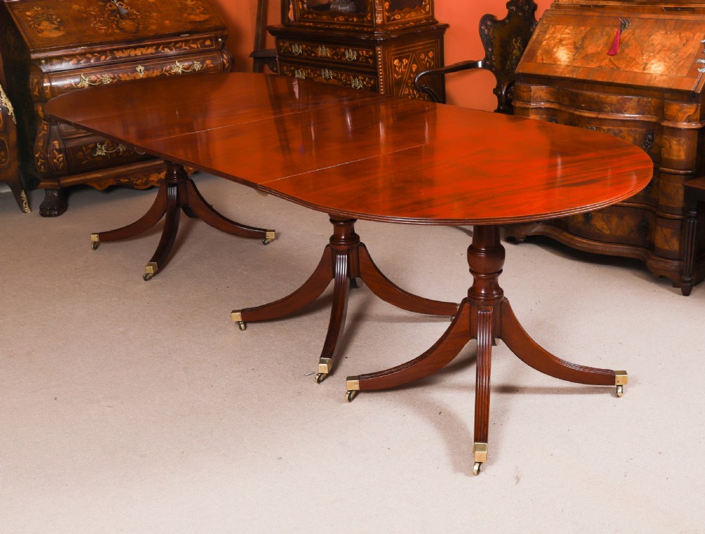 A large George IV Regency mahogany extended dining table featuring three pedestal supports with reeded legs and brass castors. View V