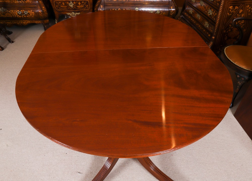 A large George IV Regency mahogany extended dining table featuring three pedestal supports with reeded legs and brass castors. View VI