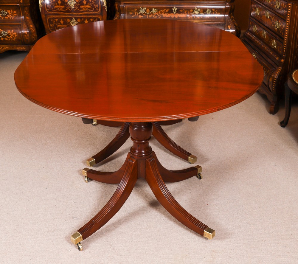 A large George IV Regency mahogany extended dining table featuring three pedestal supports with reeded legs and brass castors. View IX